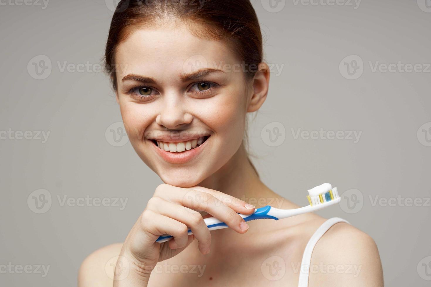 bonita mulher com uma escova de dente dentro mão manhã higiene isolado fundo foto