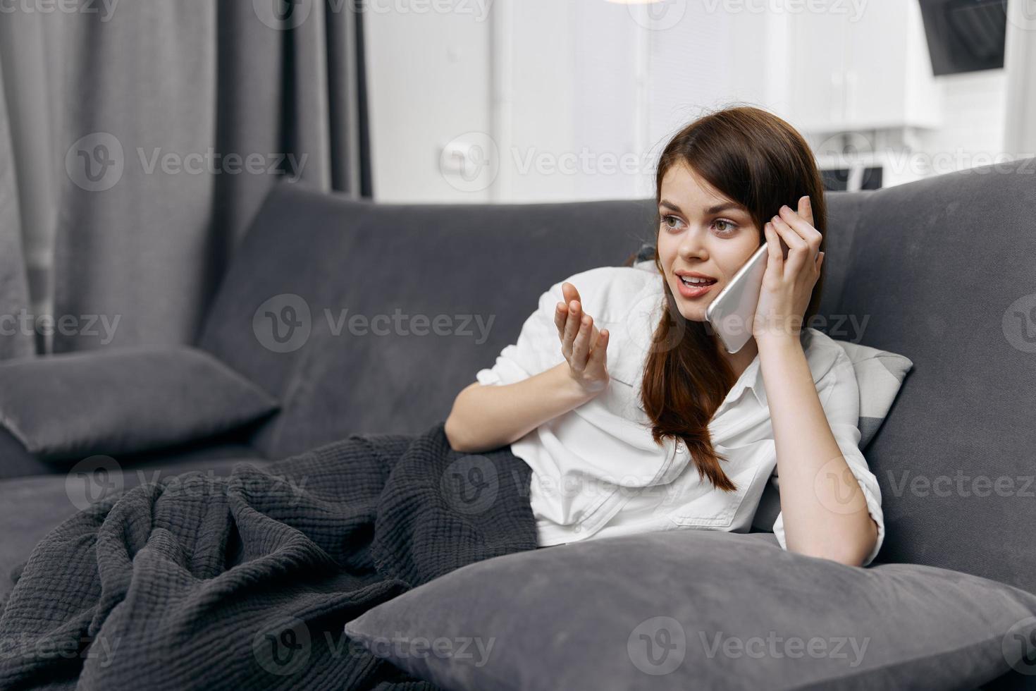mulher dentro apartamento falando em a telefone e sentado em a sofá foto