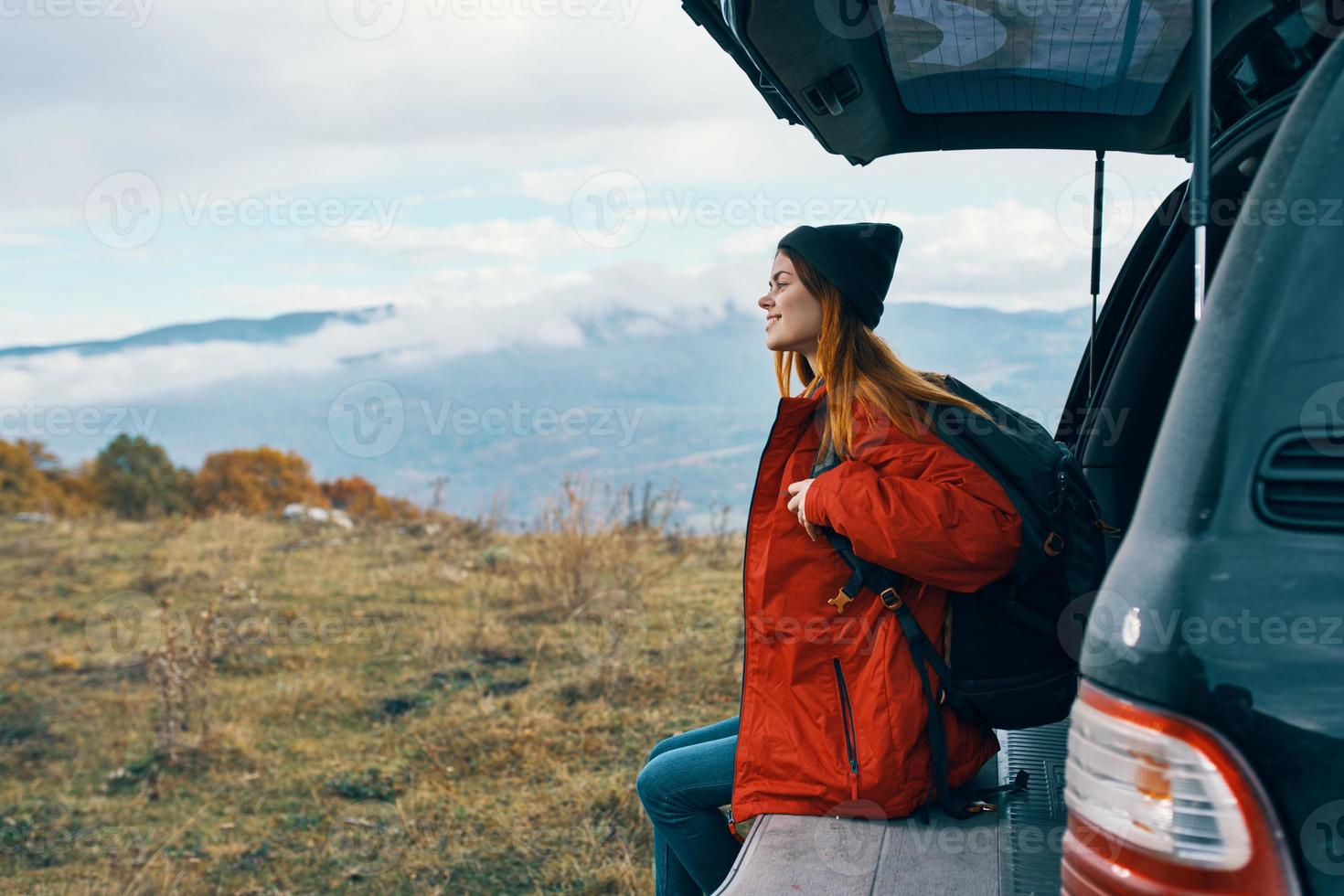 mulher caminhante dentro caloroso roupas em repouso dentro a outono dentro a montanhas perto a carro foto