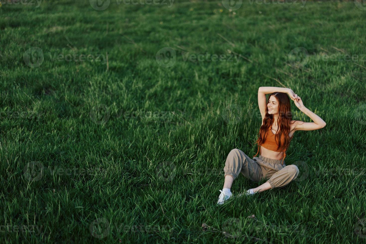 uma menina dentro confortável roupas Sentou em a Relva depois de uma andar dentro a parque para meditar e descansar dentro a luz solar foto