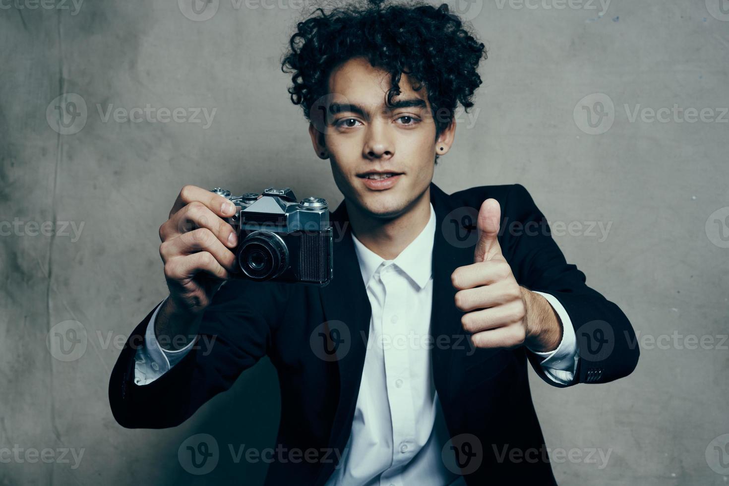 bonito cara dentro uma terno com uma Câmera lições encaracolado cabelo emoções modelo foto