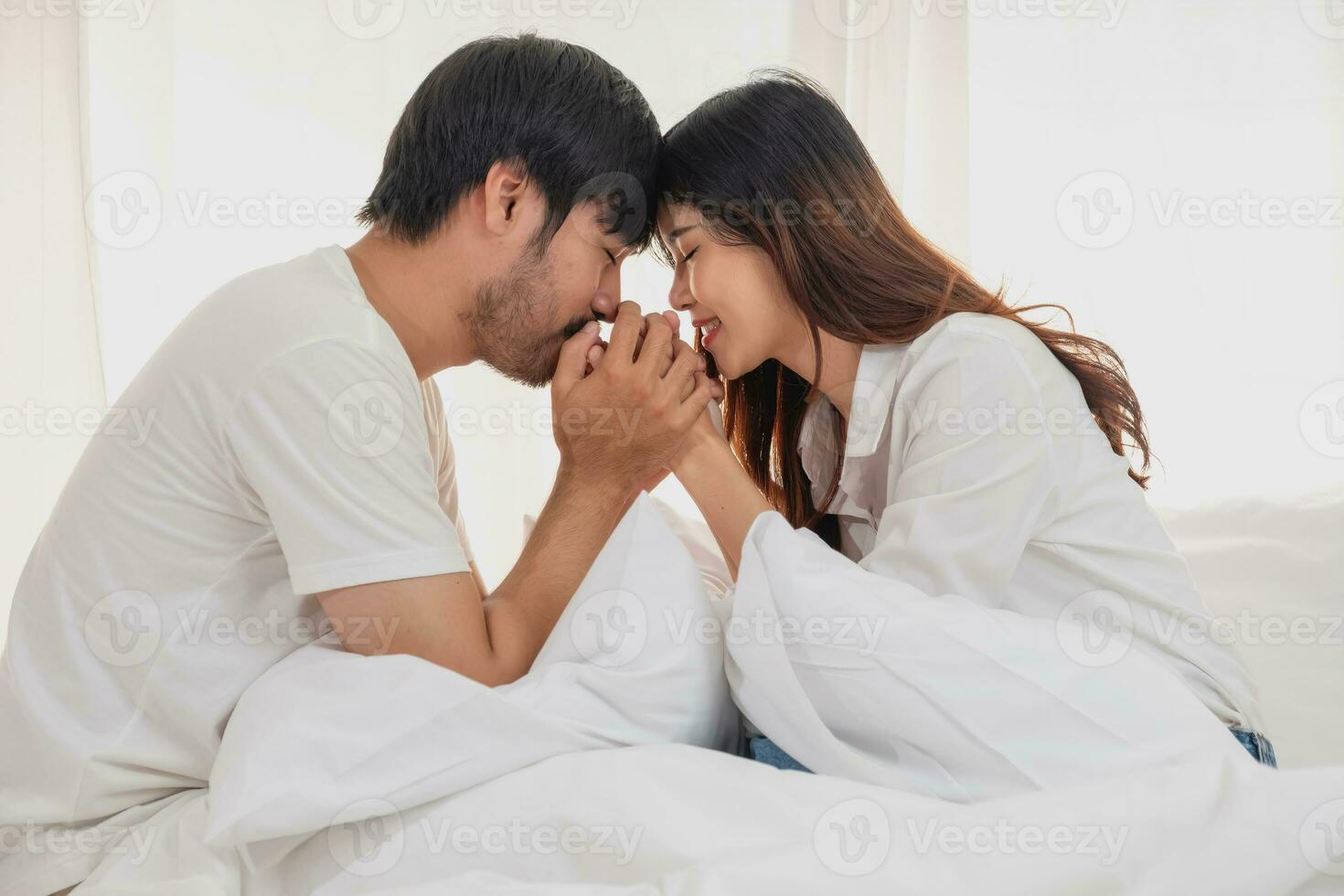 feliz jovem ásia casal abraçando, provocando, jogando alegremente dentro cama às lar, romântico Tempo para realçar família União. família conceito. foto