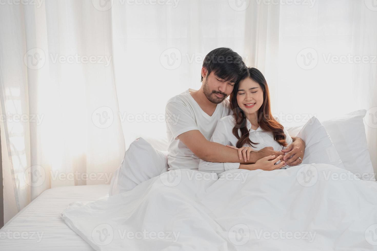 feliz jovem ásia casal abraçando, provocando, jogando alegremente dentro cama às lar, romântico Tempo para realçar família União. família conceito. foto