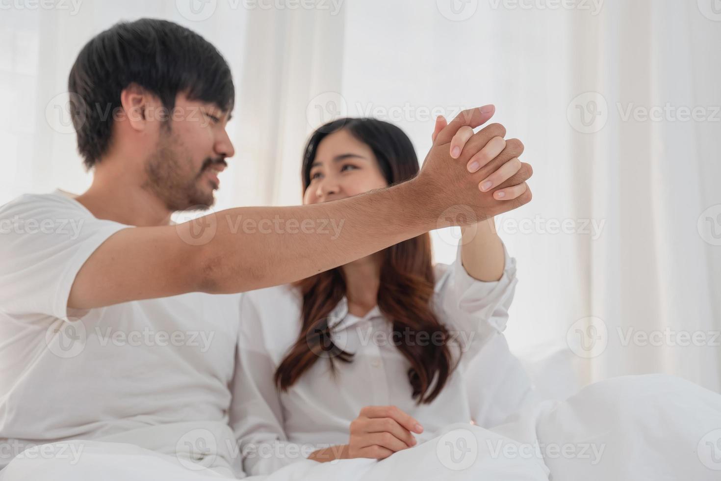 feliz jovem ásia casal abraçando, provocando, jogando alegremente dentro cama às lar, romântico Tempo para realçar família União. família conceito. foto