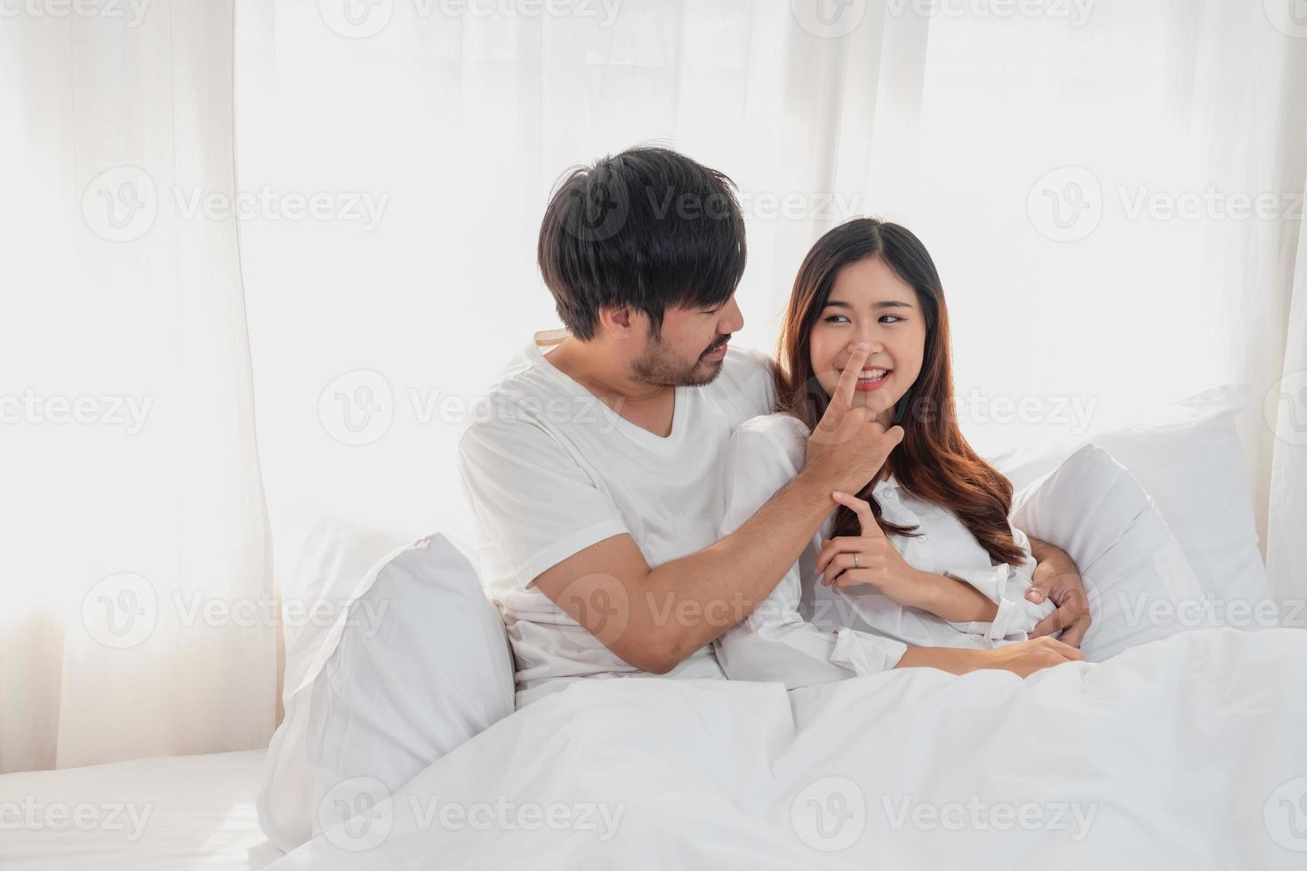 feliz jovem ásia casal abraçando, provocando, jogando alegremente dentro cama às lar, romântico Tempo para realçar família União. família conceito. foto