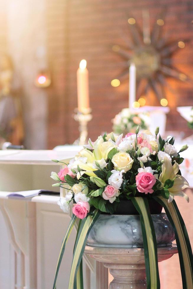 rosa flores dentro cerâmico vaso decoração em a Casamento mesa com vela cristão casado. Casamento cerimônia dentro cristão Igreja foto