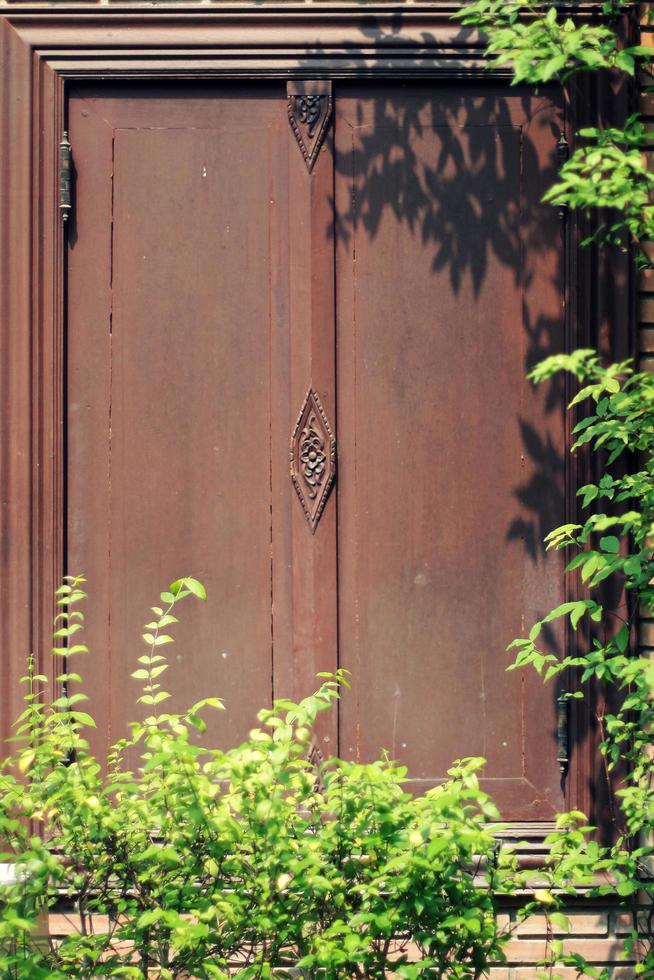 árvore sombras dentro a jardim em Antiguidade tailandês estilo de madeira janela em tijolo muro. vintage conceito. foto