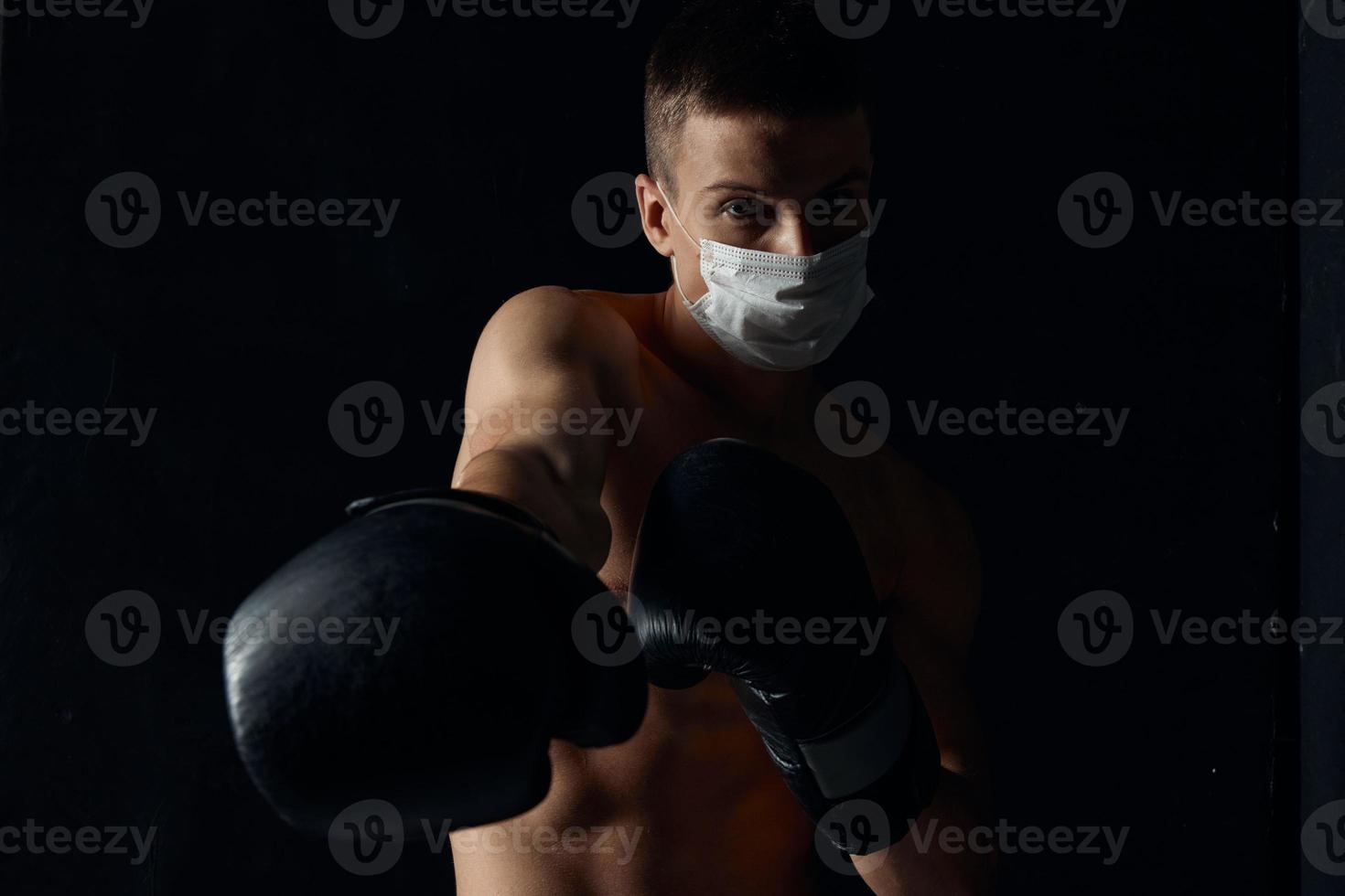 boxer dentro uma médico mascarar e boxe luvas em uma Preto fundo cópia de espaço foto