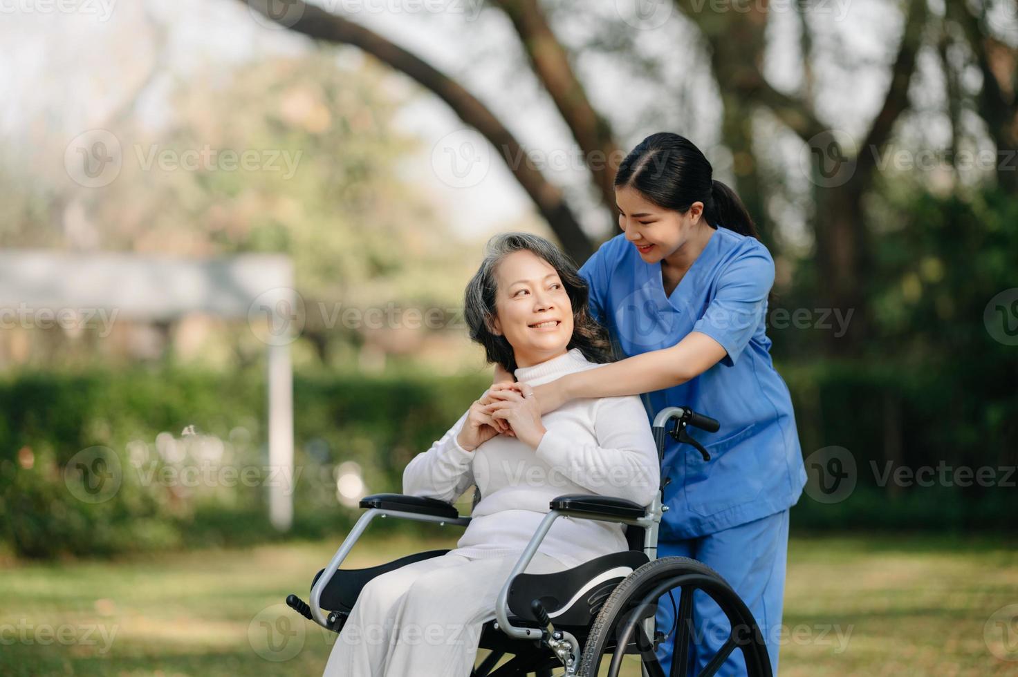 idosos ásia Senior mulher em cadeira de rodas com ásia Cuidado cuidador e encorajar paciente, caminhando dentro jardim. com Cuidado a partir de uma cuidador e Senior saúde seguro. foto