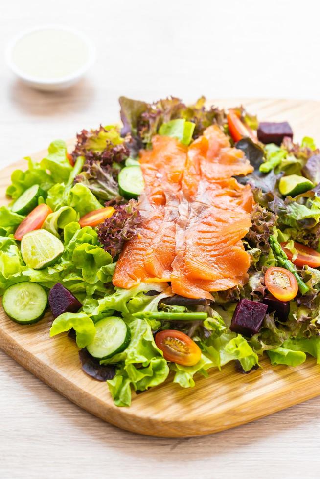 Peixes crus de carne de salmão defumado com salada de vegetais verdes frescos foto