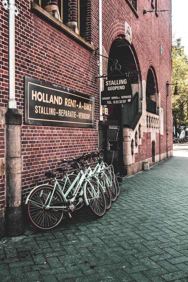 amsterdam, holanda 2015 - estande da bicicleta ao lado de um prédio de tijolos foto