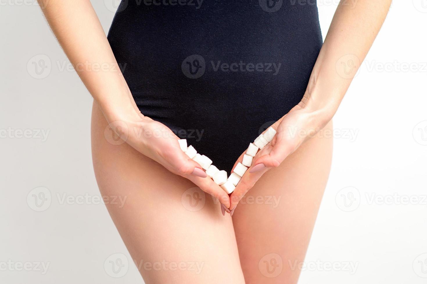mulher segurando açúcar cubos em bikini zona, a conceito do íntimo depilação, problemas do íntimo higiene. foto