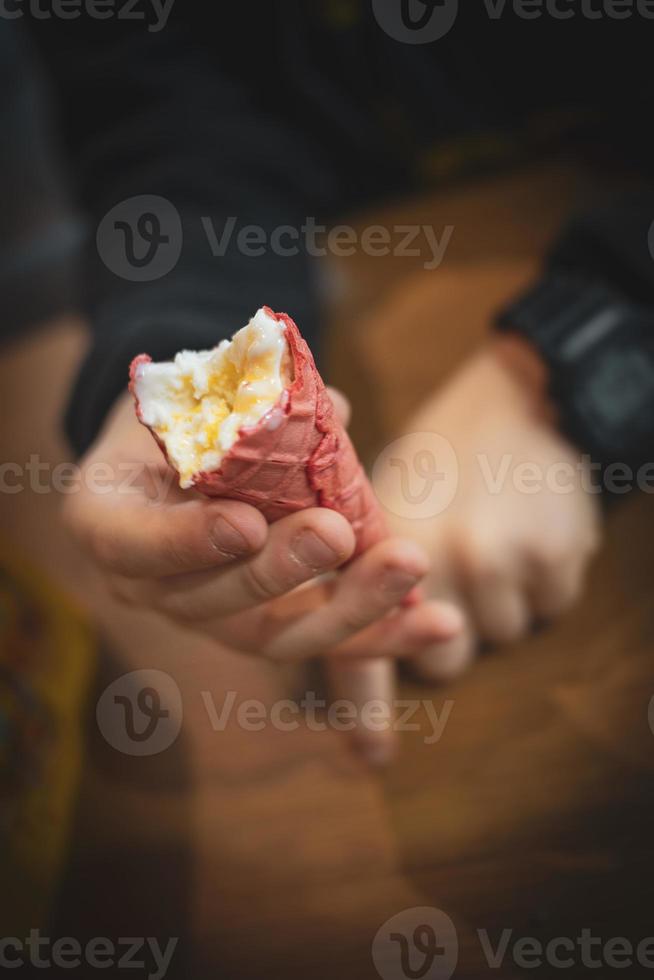 saboroso frio cremoso baunilha gelo creme dentro uma vermelho açúcar cone mantido dentro seu mão foto