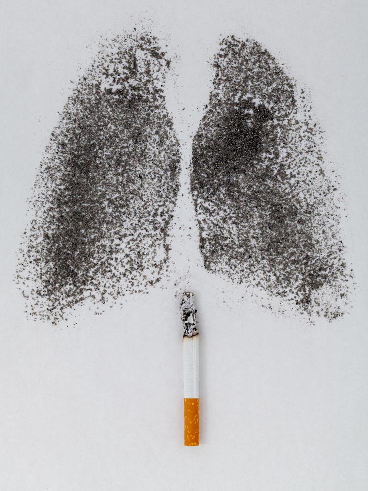 forma de pulmão com pó de carvão e cigarro em fundo branco foto