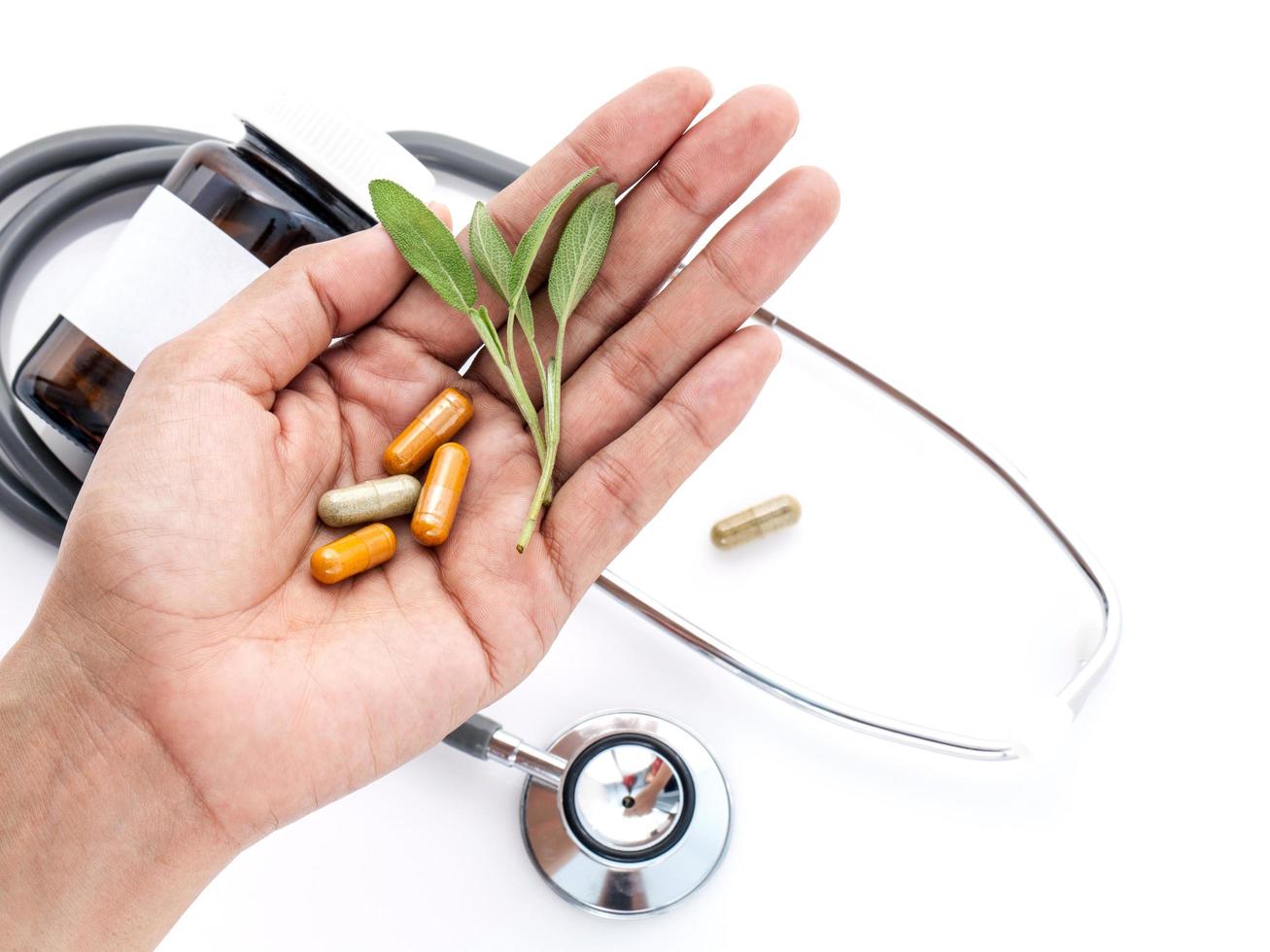 cápsulas de ervas frescas de cuidados de saúde alternativos nas mãos do médico sobre fundo branco foto