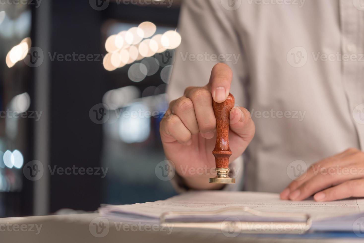 homem carimbando a aprovação de documentos bancários de finanças de trabalho ou de marketing de investimento na mesa. foto