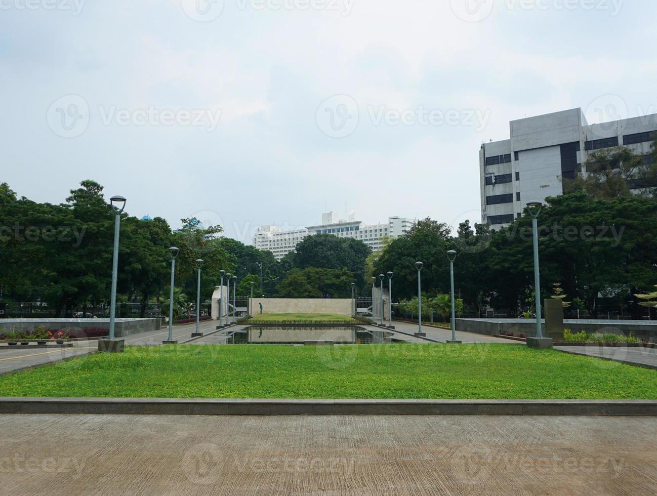 Visão do pessoas rega a jardim quintal. isto parque é cercado de vegetação e de várias jardim postes de iluminação foto