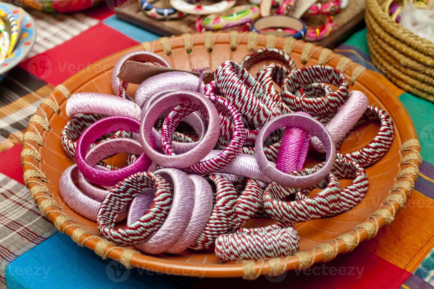 variedade colori feito à mão pulseiras estão exibido com em alguns pequeno cestas para oferta. foto