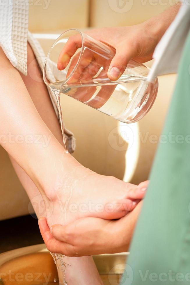 mãos do terapeuta lavando pernas foto