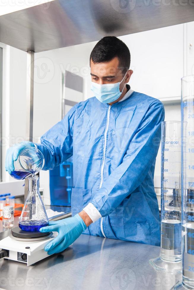 jovem masculino cientista trabalhando com a agitador às laboratório vestido dentro azul foto