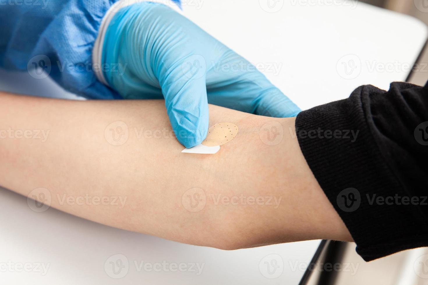 enfermeira colocando uma curativo em uma pacientes braço depois de levando uma sangue amostra foto