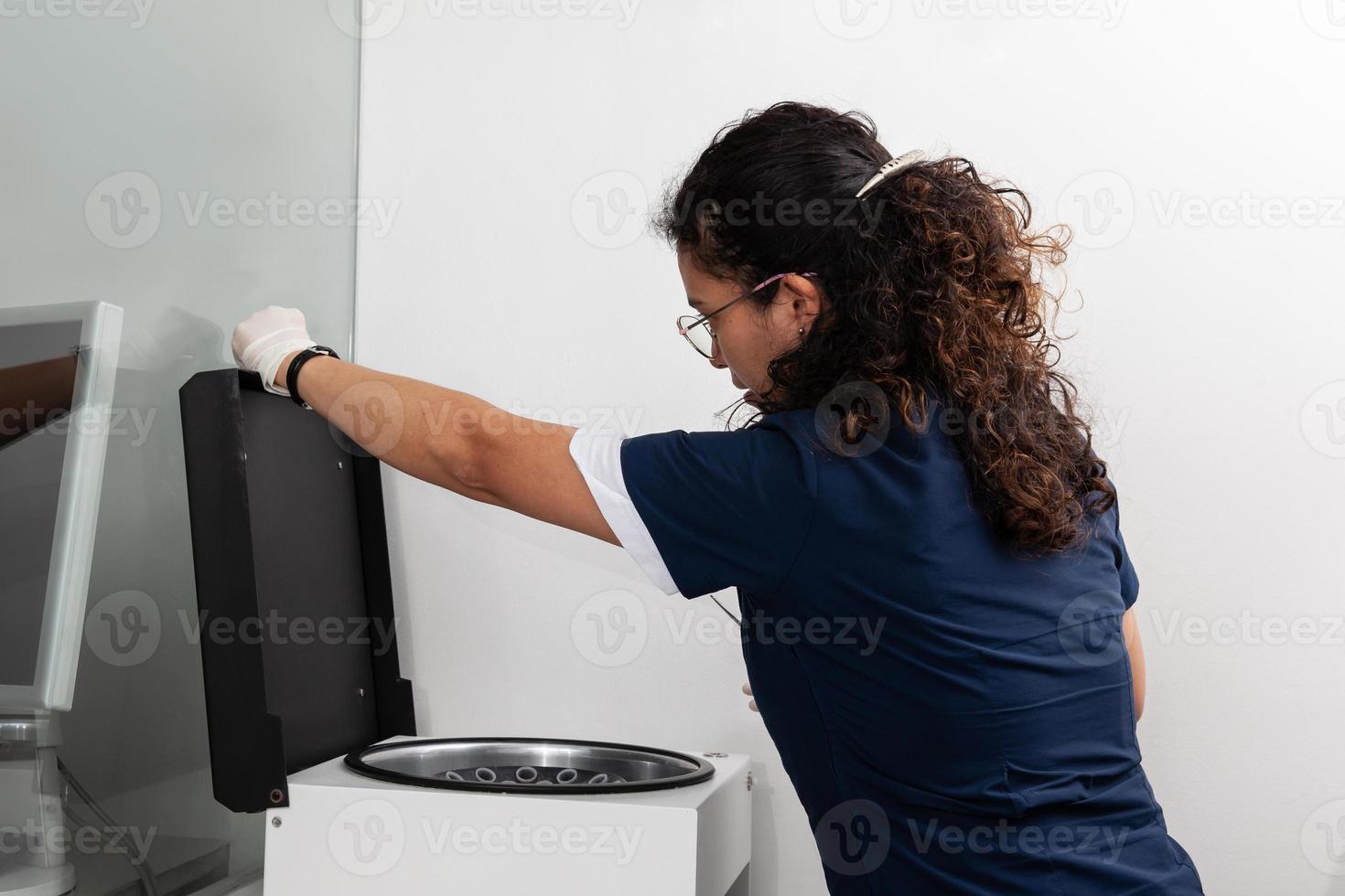 jovem fêmea cientista usando uma centrífuga dentro a laboratório. foto