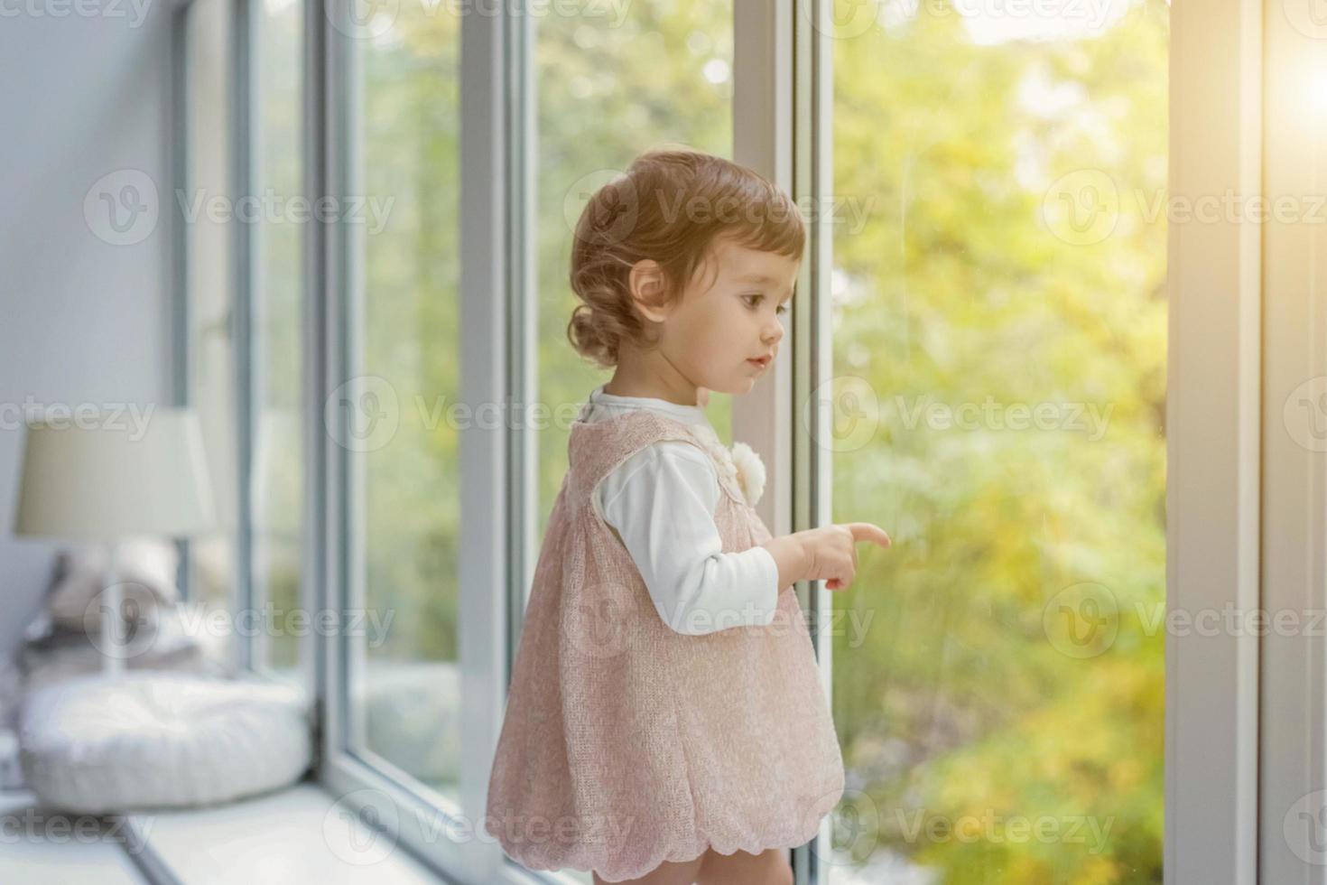 pequeno menina em pé em janela peitoril foto