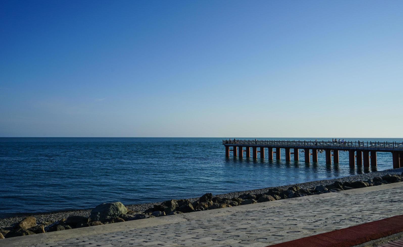 cais de atracação em um mar azul calmo e um céu azul claro em sochi, na rússia foto