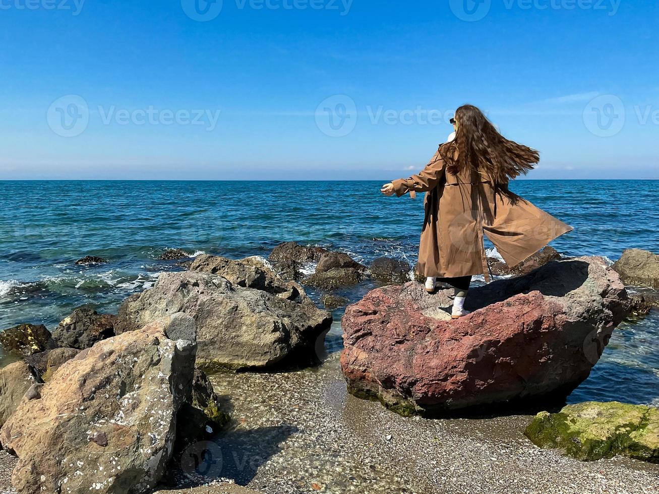 menina com grandes cabelo é em pé em Beira Mar vestido foto