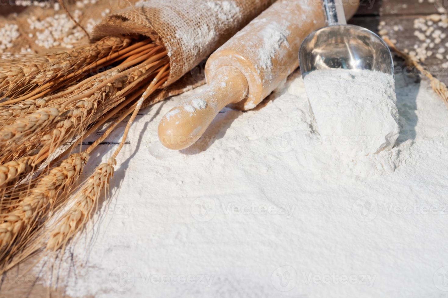 farinha e orelhas do trigo, cevada, culinária, pão, e biscoitos estavam arranjado em a de madeira mesa fundo dentro uma rústico cozinha. topo visualizar. foto