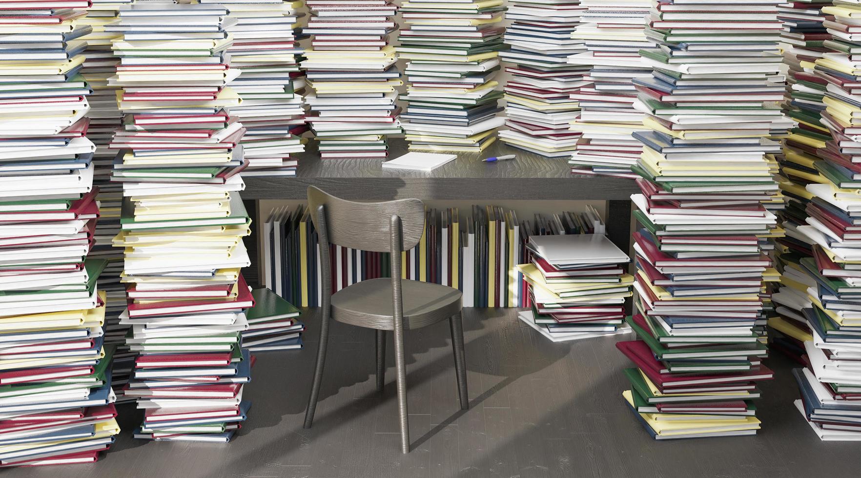 mesa cercada por muitos livros empilhados ao redor foto