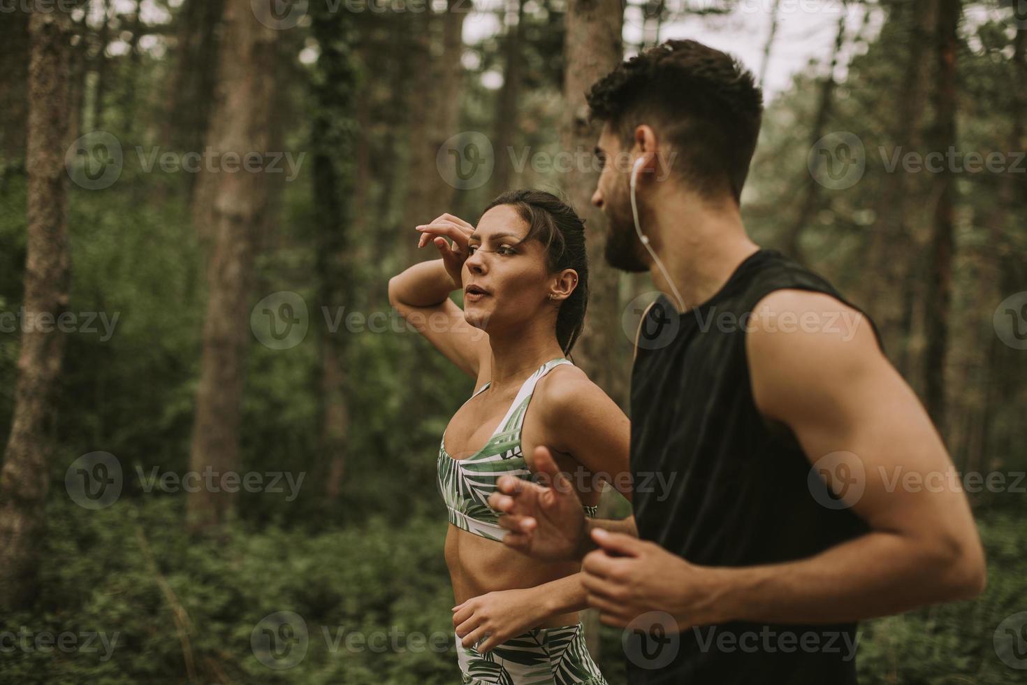 jovem casal fitness correndo na trilha da floresta foto