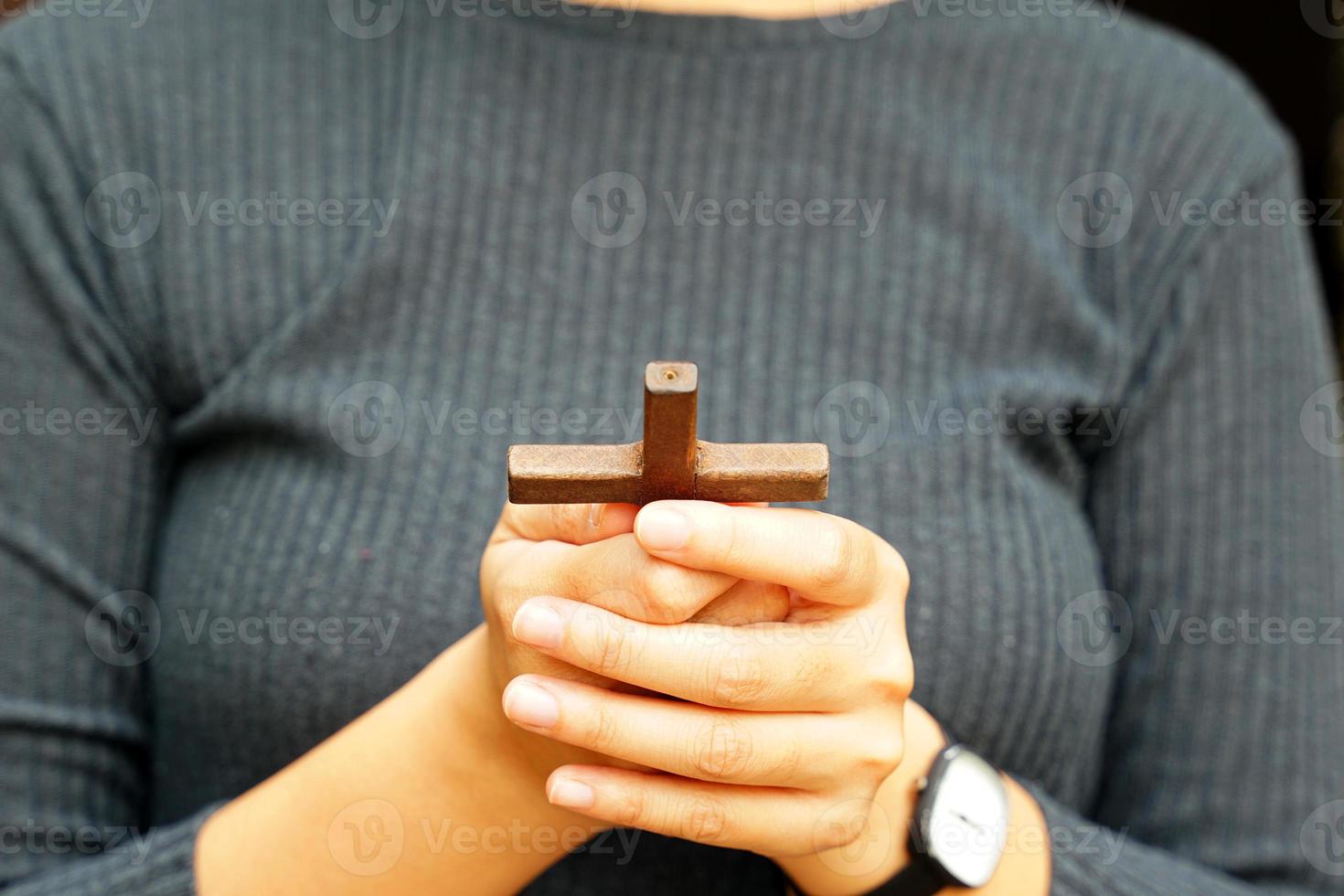 de madeira Cruz segurando dentro mãos do a ásia mulher, conceito para ter esperança, amor, perdão e crença dentro Jesus por aí a mundo. suave e seletivo foco. foto