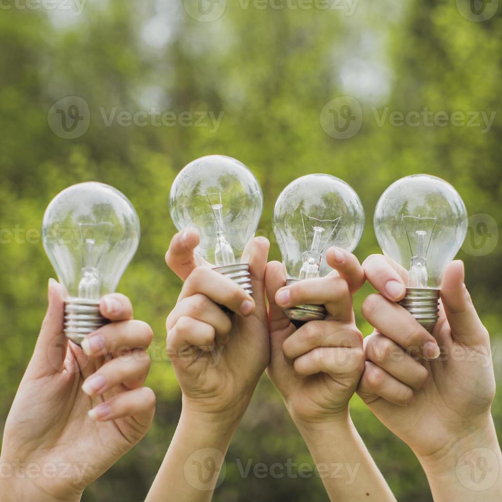 mãos segurando lâmpadas no ar na natureza foto