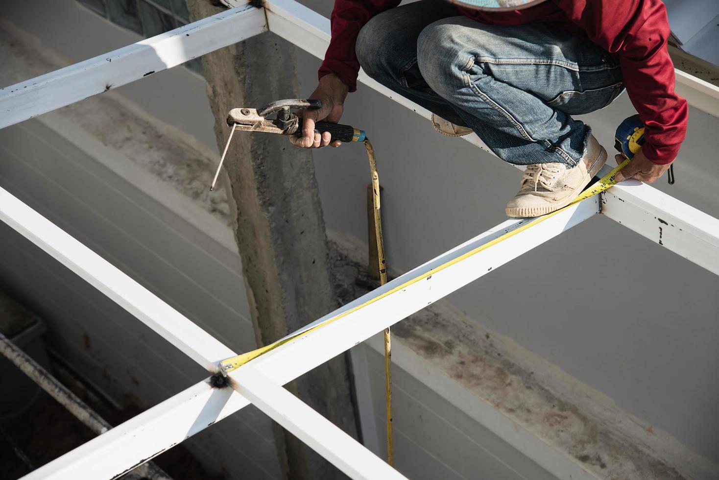 o homem da construção está soldando a estrutura do telhado de aço, as pessoas que trabalham no conceito de canteiro de obras foto