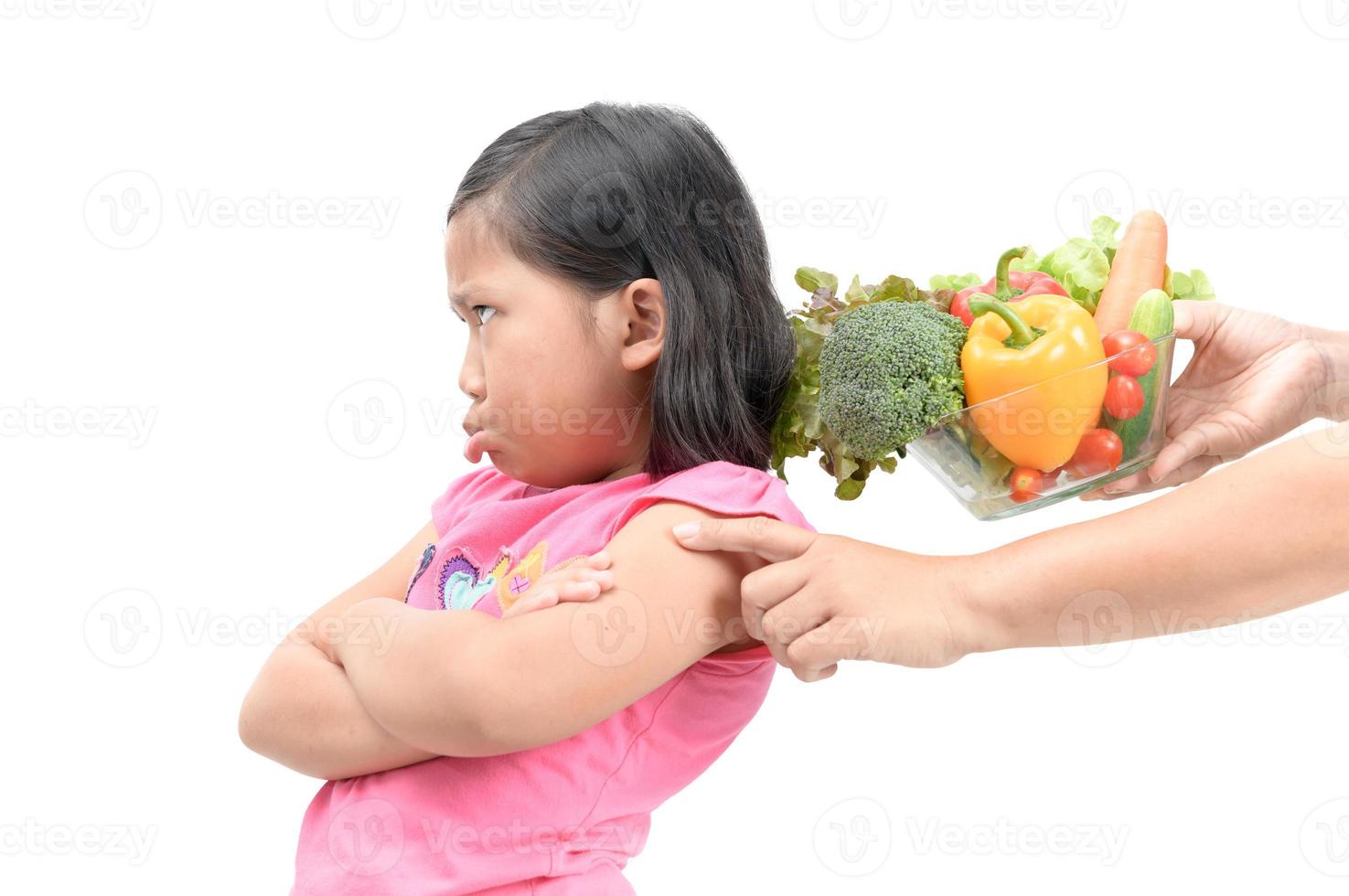 menina com expressão do nojo contra legumes foto