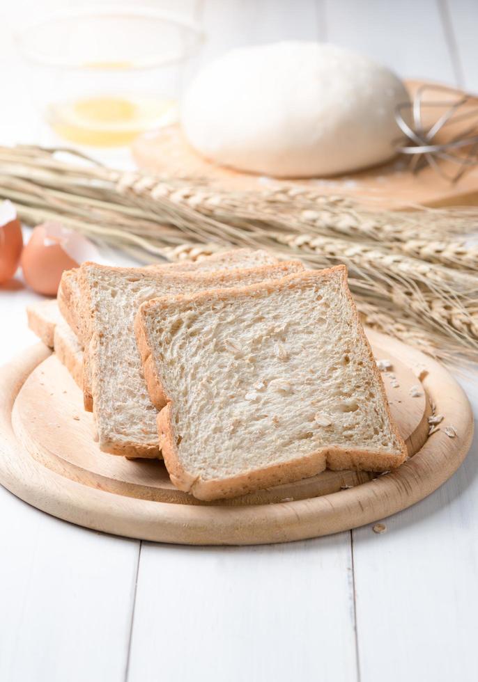 fatia trigo pão em branco madeira fundo foto