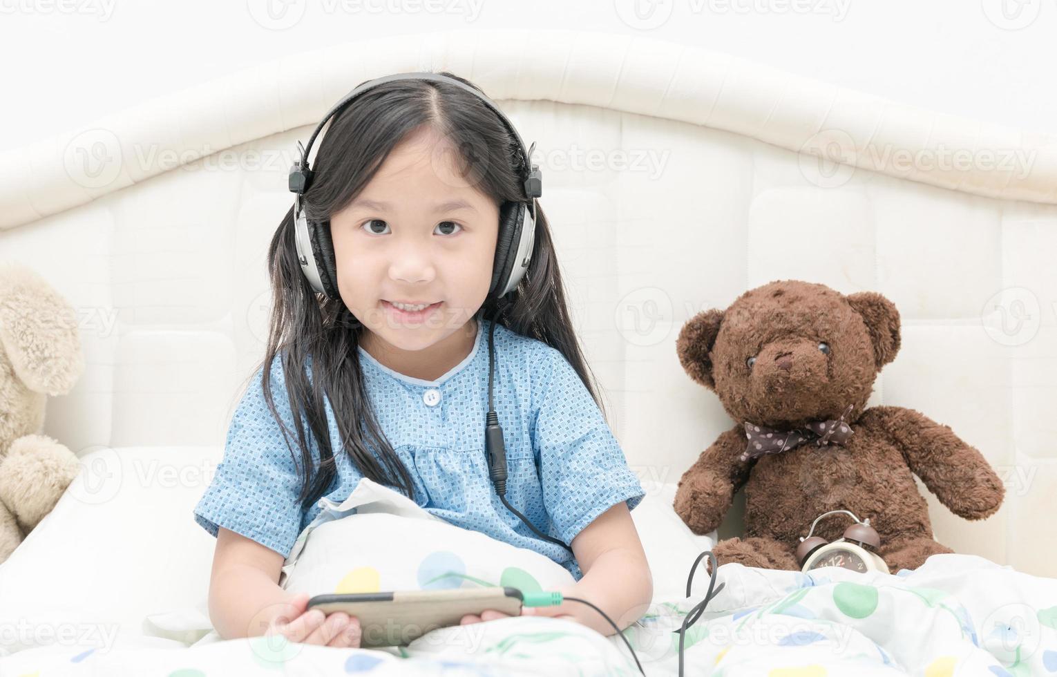 fofa menina jogando Móvel telefone com fone de ouvido foto