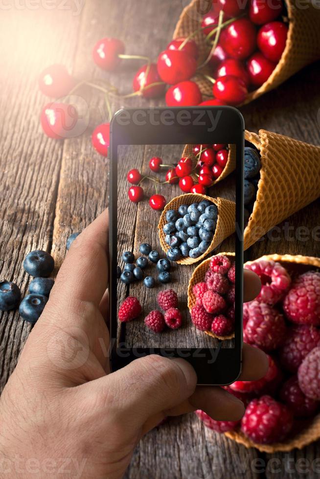 homem fotografando frutas dentro gelo creme cone foto