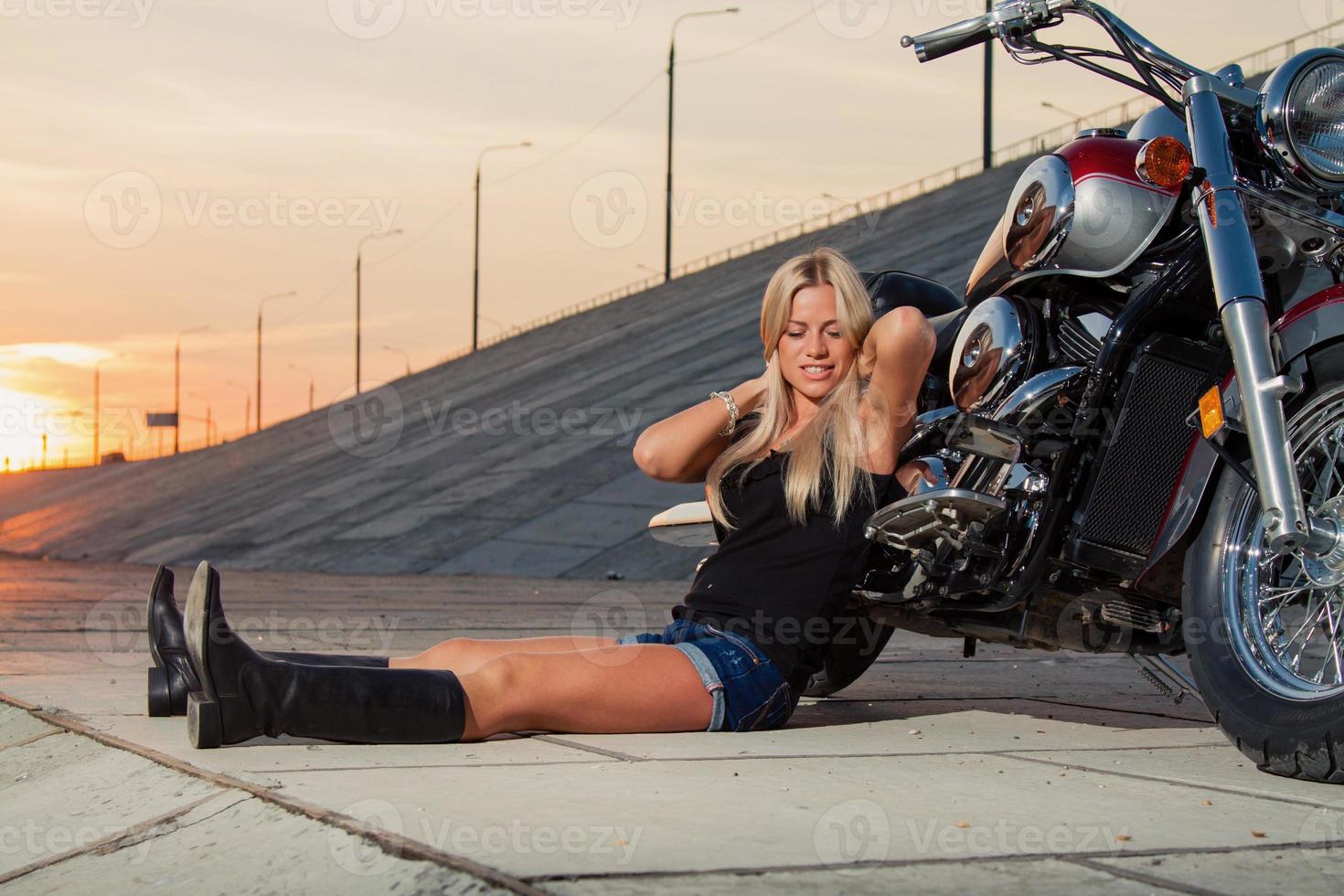 loira sexy sentada perto de sua motocicleta foto