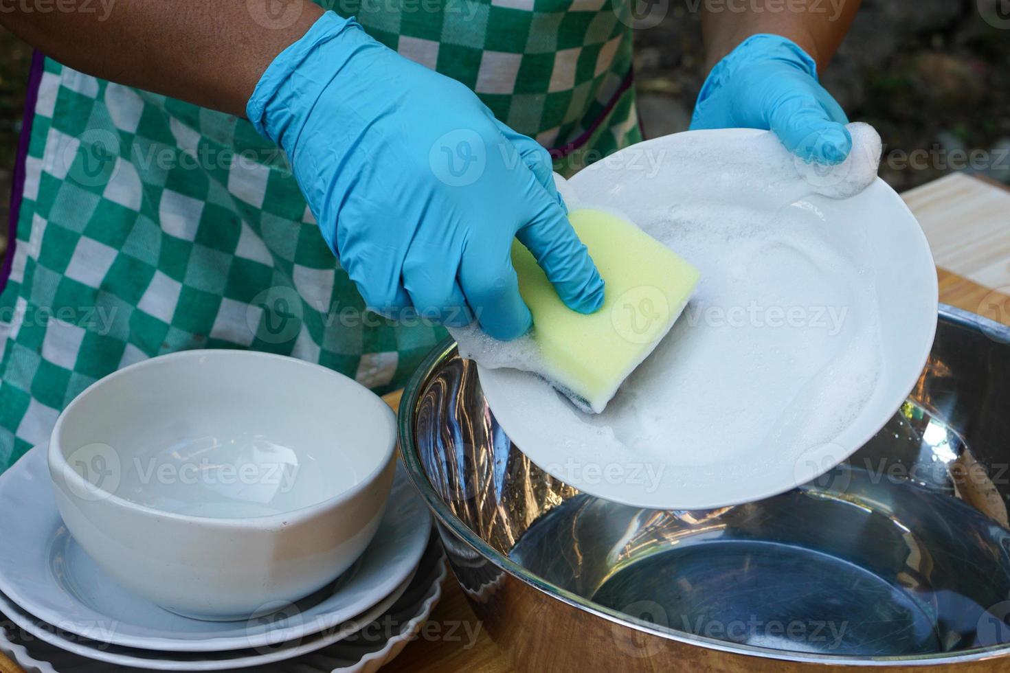 fechar-se mão desgasta azul luvas, detém esponja para lavar prato. conceito diariamente tarefa, tarefas domésticas. limpeza depois de refeições. dever dentro cozinha. foto