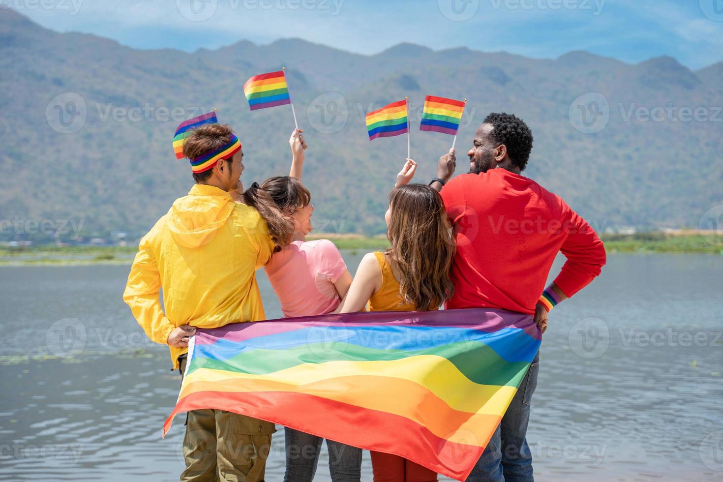 costas visualizar. jovem diversidade pessoas tendo Diversão segurando lgbt arco Iris bandeira em a de praia. apoiantes do a lgbt comunidade foto