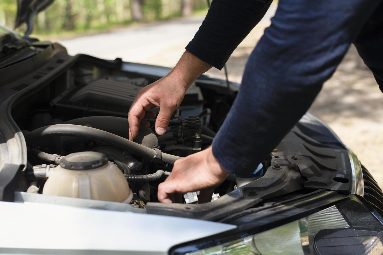 uma homem em a lado do a estrada é fixação uma carro. mãos em a capuz. carro reparar em a estrada. máquina demolir foto