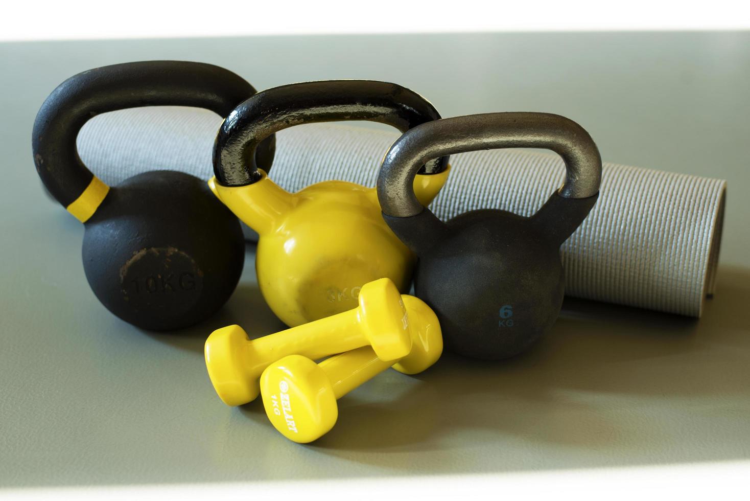 três Kettlebells e cinzento ioga esteira foto