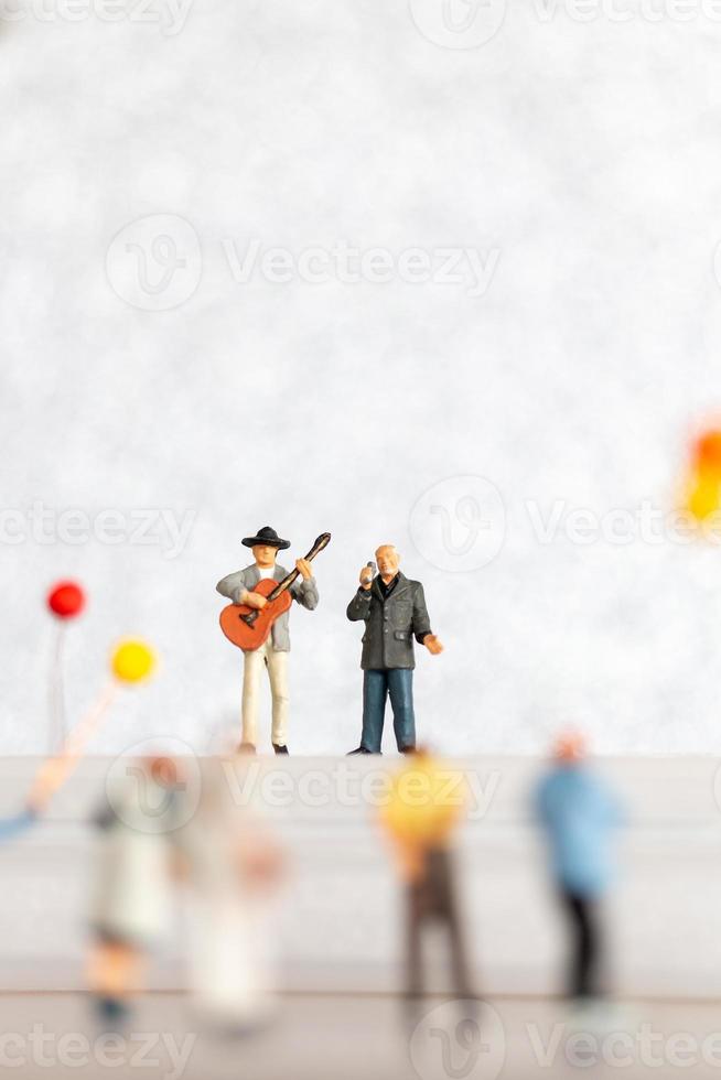 miniatura cantor e músico jogando uma guitarra em estágio, mundo música dia conceito foto