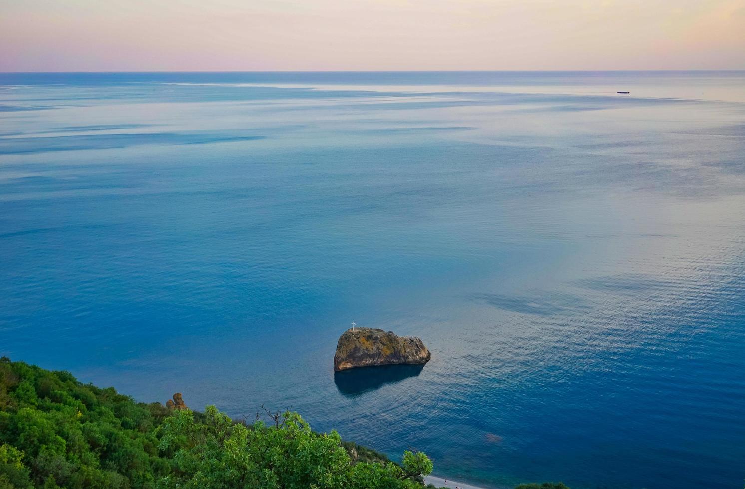 paisagem marinha de uma costa rochosa por um corpo de água com um céu nublado colorido foto