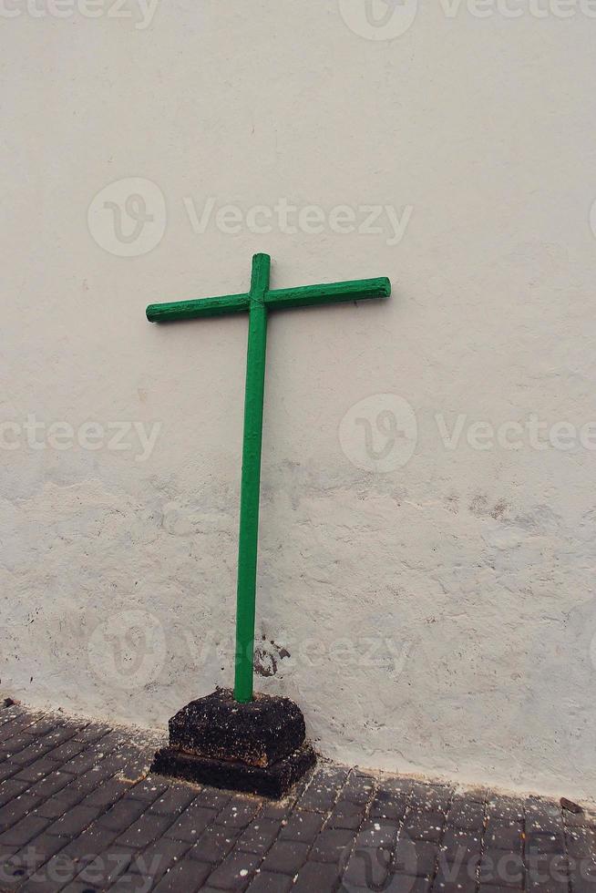 uma verde de madeira Cruz em a rua Sediada em a velho branco casa em a ilha do Lanzarote foto