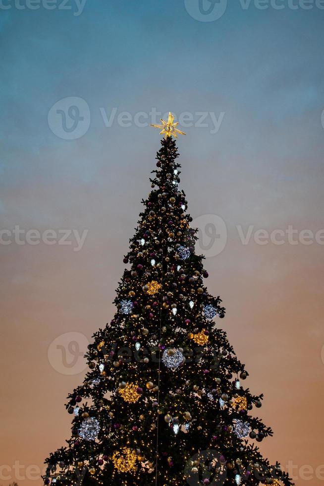 colorida Natal árvore cintilante contra a fundo do a tarde pastel céu foto