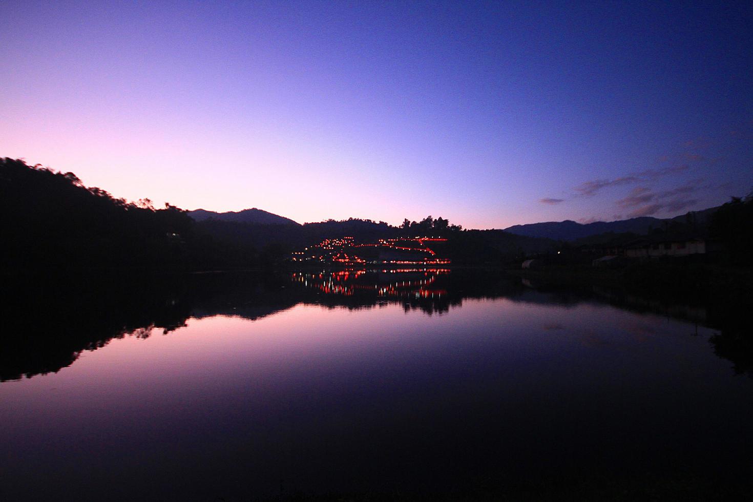 lindo pôr do sol e crepúsculo do céu reflexão em água superfície e lago às Colina tribo Vila dentro Tailândia foto