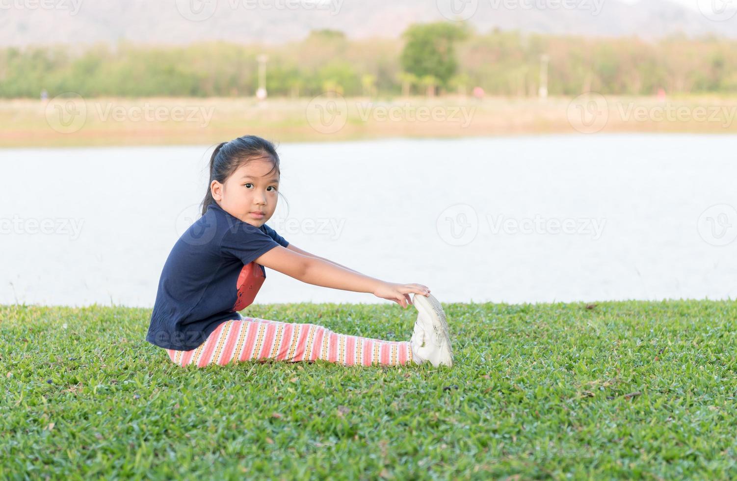 fofa ásia menina exercício em verde Relva foto